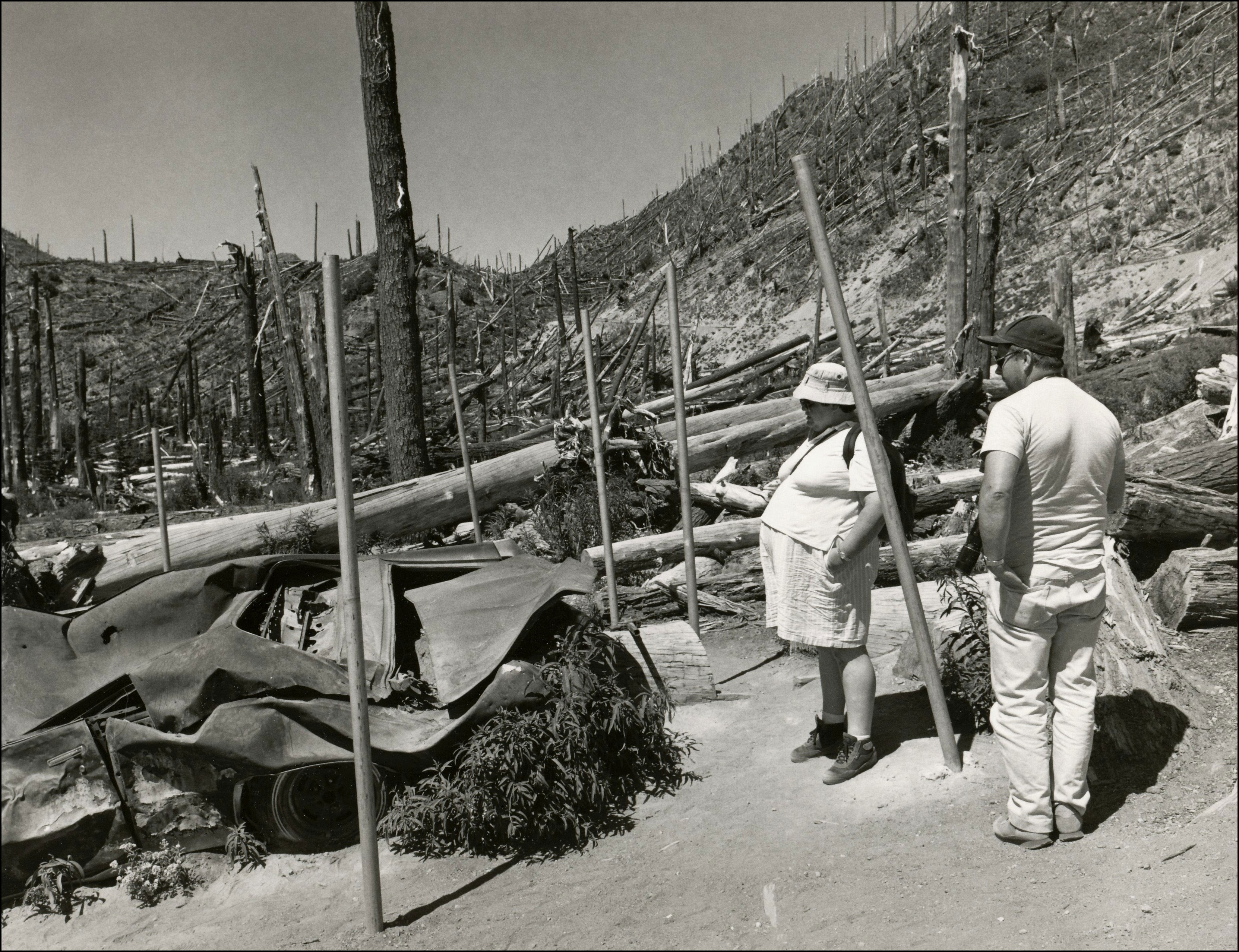 Couple looking out on a trail that that goes through the remainder of a forest after the Mount St. Helens volcano eruption