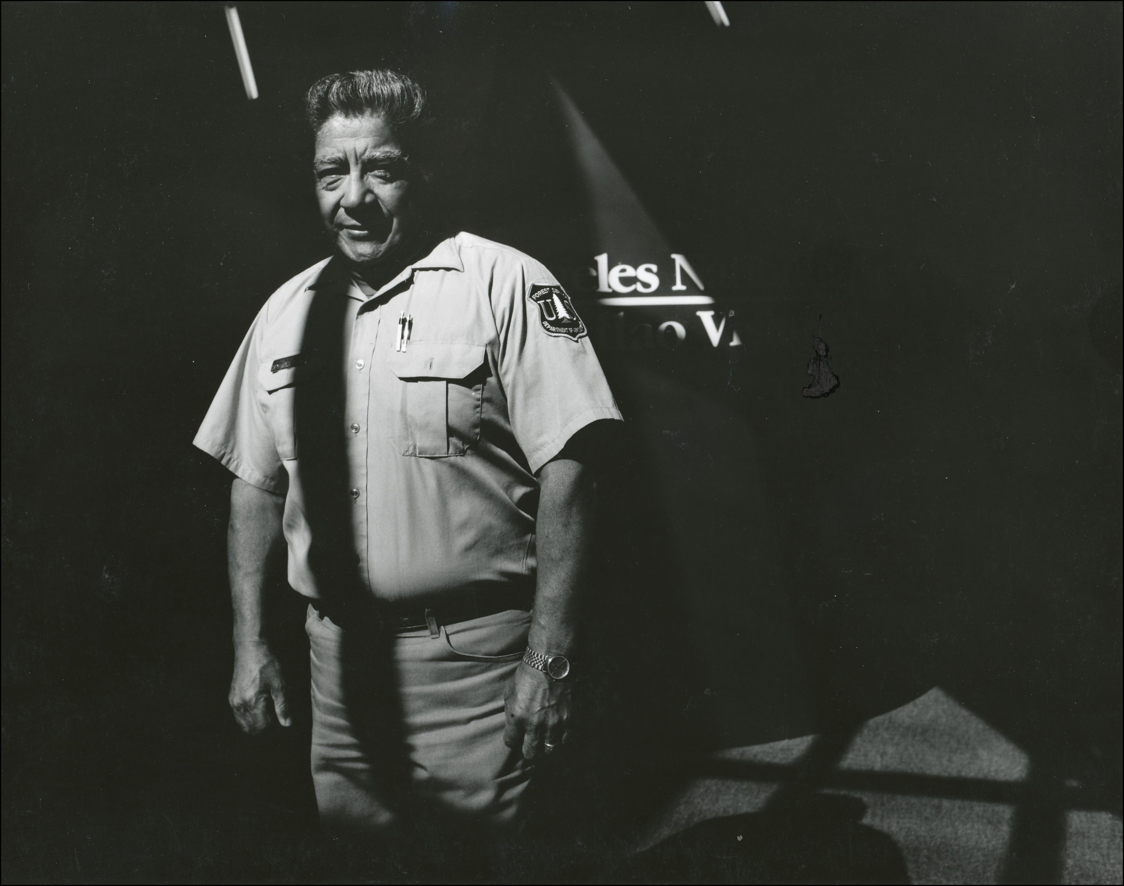 Forest service worker in uniform posing inside a dark building with sunlight coming in from a source above