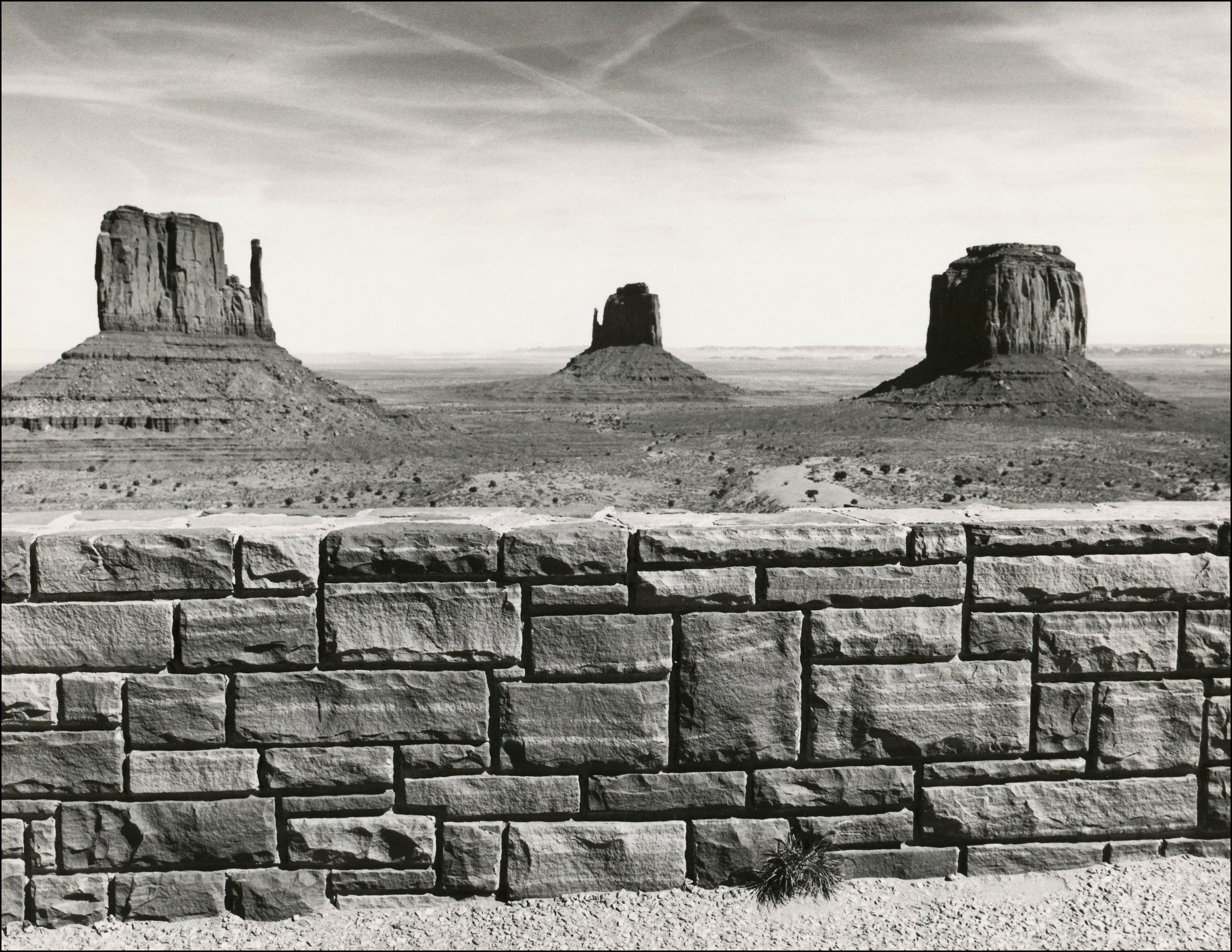 view of the mittens in monument valley with stone fence in foreground
