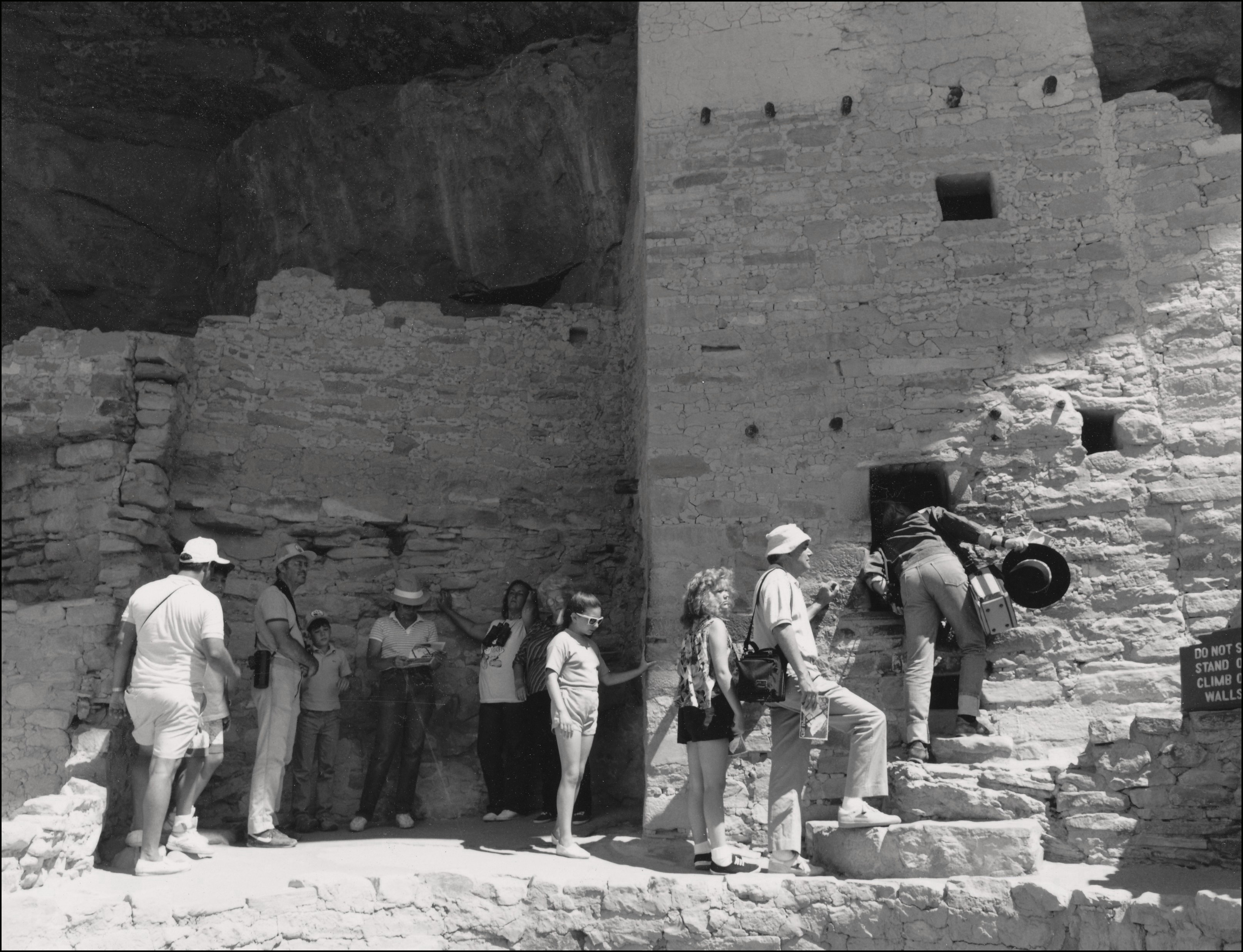 several people waiting in line to look through the window of an old ruin