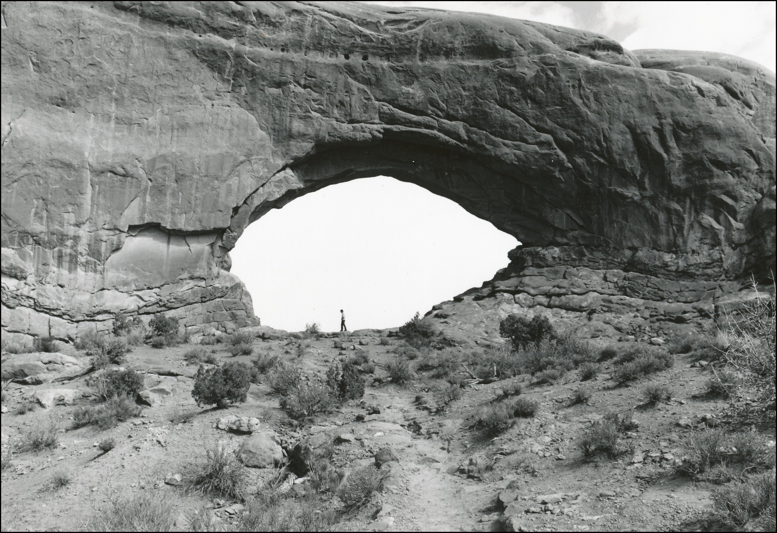 Person under large rock arch